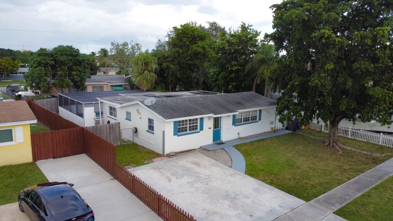 Aerial drone exterior shot of white home with blue accents in West Palm Beach FL