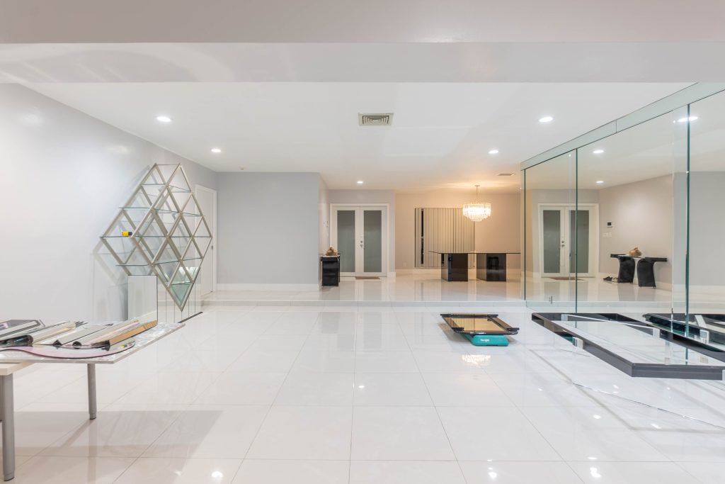 Spacious open plan living area with white tile floors and mirror wall