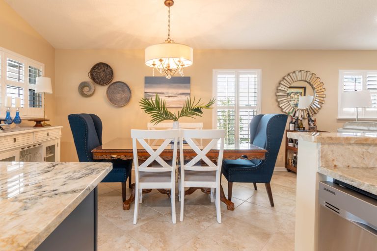 Bright dining room with marble countertops, pendant light, and navy accent chairs